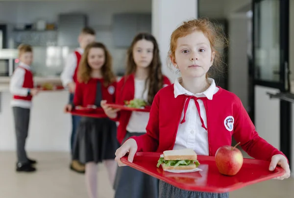 Niños Felices Uniformes Sosteniendo Bandejas Con Almuerzo Pie Una Cola — Foto de Stock