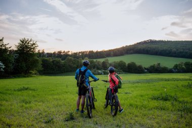 Yaz parkında bisiklete binen aktif yaşlı bir çift, sağlıklı yaşam tarzı kavramı..