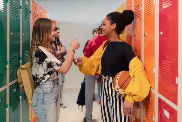 Young high school students meeting and greeting near locker in a campus hallway, back to school concept.