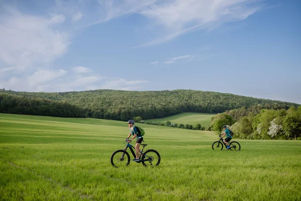 夏の公園を通る電動自転車に乗るアクティブなシニアカップル 健康的なライフスタイルコンセプト — ストック写真