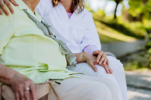 Close Caregiver Consoling Senior Woman Touching Her Hand Sitting Bench — Φωτογραφία Αρχείου