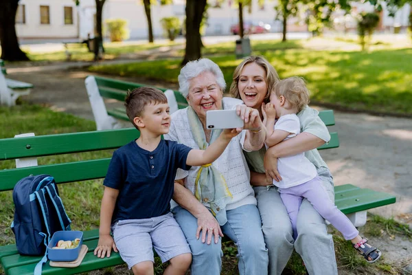 Prababcia Robi Sobie Selfie Swoją Wnuczką Dziećmi Siedząc Latem Parku — Zdjęcie stockowe