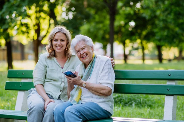 Egy Felnőtt Nagypapa Segít Nagyanyjának Mobilt Használni Amikor Nyáron Padon — Stock Fotó