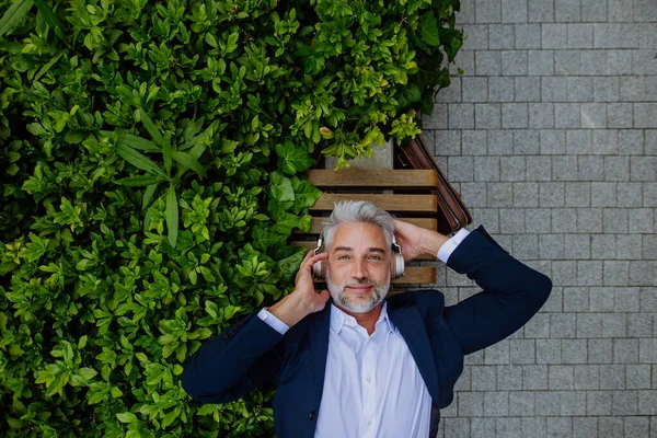 Yetişkin Bir Adamının Arasında Şehir Parkındaki Bankta Dinlenen Kulaklıklarla Müzik — Stok fotoğraf