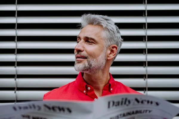 バルコニーに座って新聞を読む成熟した実業家 — ストック写真