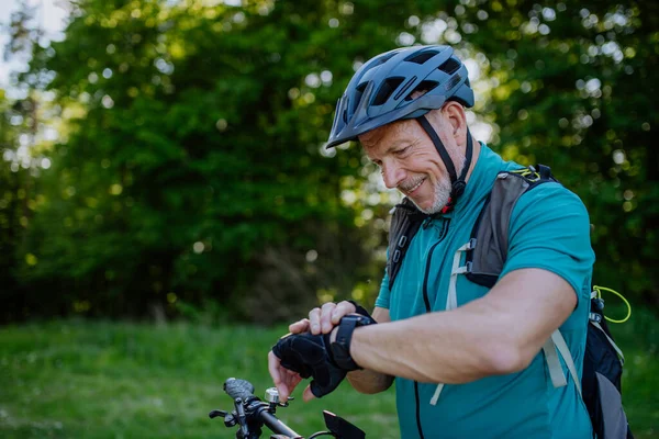 Active Senior Man Riding Bicycle Summer Park Looking Smartwatch Checking — 스톡 사진