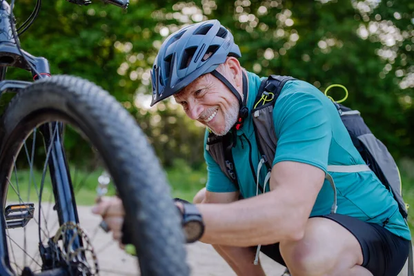 Active Senior Man Repairing Bicycle Pumping Tire Nature Summer — стоковое фото