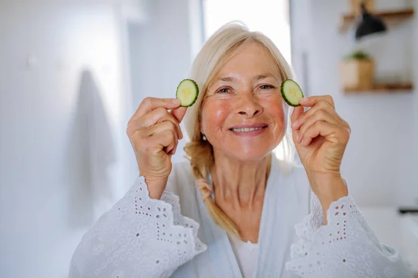 Eine Schöne Seniorin Bademantel Trägt Gurken Gesichtsmaske Badezimmer Auf Hautpflegekonzept — Stockfoto