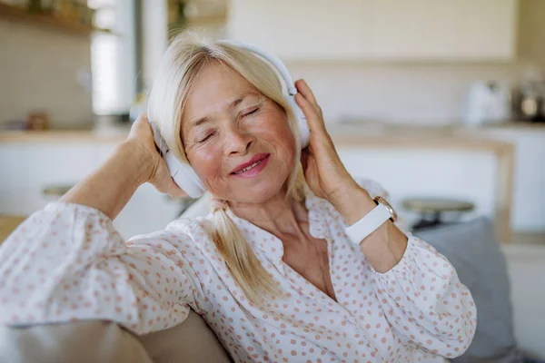 A senior woman with headphones listening to relaxation music at home