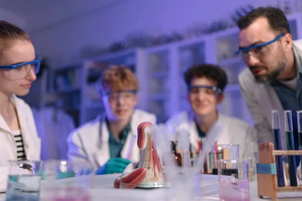 Science students with a teacher doing chemical reaction experiment in the laboratory at university.