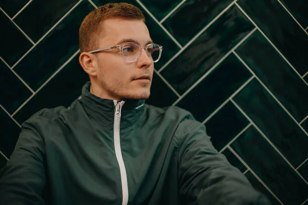 Portrait Young Man Jacket Glasses Sitting Agiant Dark Tiled Wall — Stock Fotó