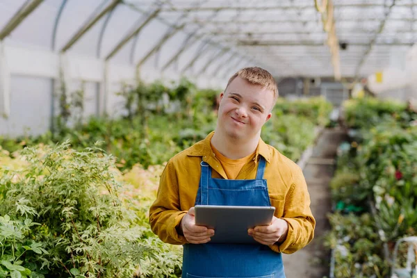 庭の中心で働いてるダウン症候群の若い男クリップボードとチェック植物 — ストック写真