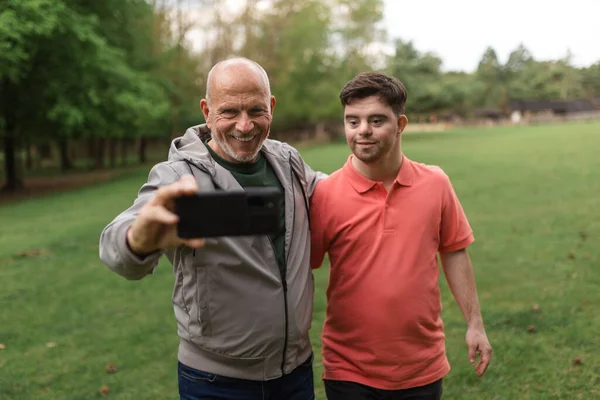 Happy Senior Father His Young Son Syndrome Taking Selfie Park — Foto Stock