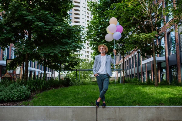一个快乐精力充沛的成熟商人拿着气球走在墙上 感到自由 工作生活平衡的有趣的肖像 — 图库照片