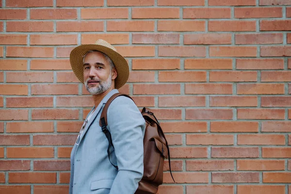 カメラを見ながら藁帽子とリュックを身に着けている自信のある男の肖像画 仕事に向かう途中の夏にカジュアルな服を着たビジネスマン — ストック写真
