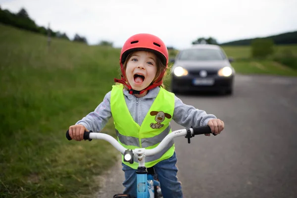 Portrait Excited Little Girl Reflective Vest Riding Bike Road Car — стоковое фото