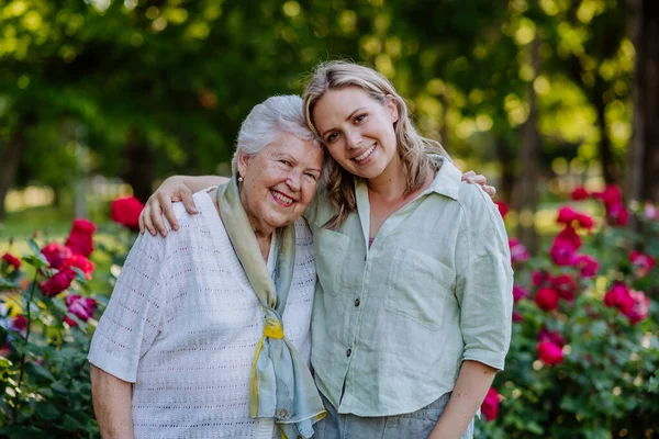 Retrato Neta Adulta Com Avó Sênior Passeio Parque Com Rosas — Fotografia de Stock