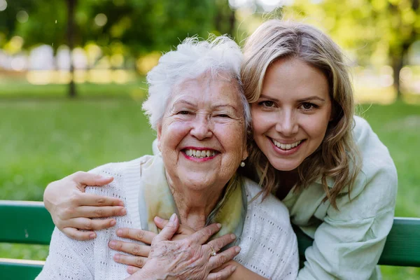 Portrait Adult Granddaughter Hugging Her Senior Grandmother Sitting Bench Park — ストック写真