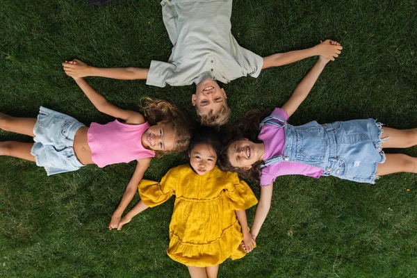 Happy Four Friends Lying Grass Holding Each Other Hands Having — Stock Photo, Image