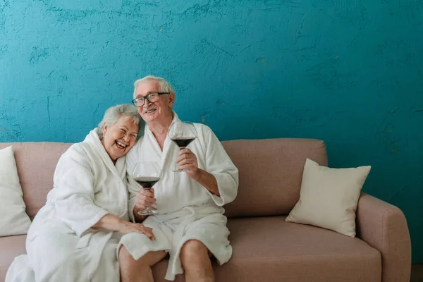 Happy Senior Couple Sitting Together Bathrobe Sofa Glass Wine Having — 스톡 사진