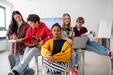 Bir grup öğrenci bir robotik sınıfında birlikte oturup poz veriyorlar.