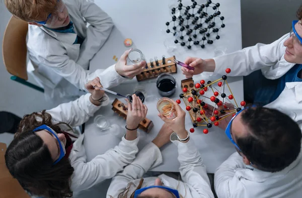 Science students doing a chemical experiment in the laboratory at university. Top view.