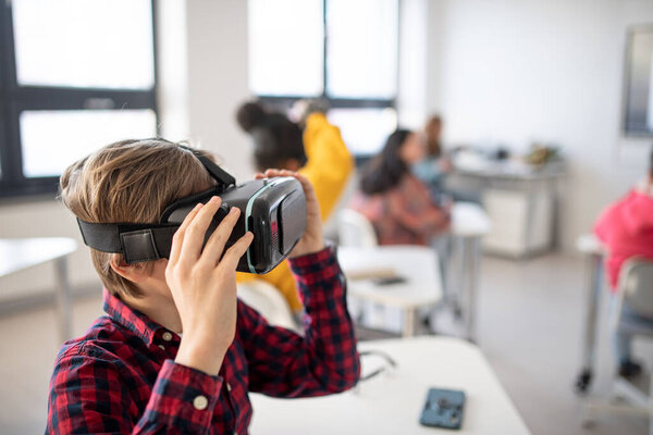 Curious student wearing virtual reality goggles at school in a computer science class