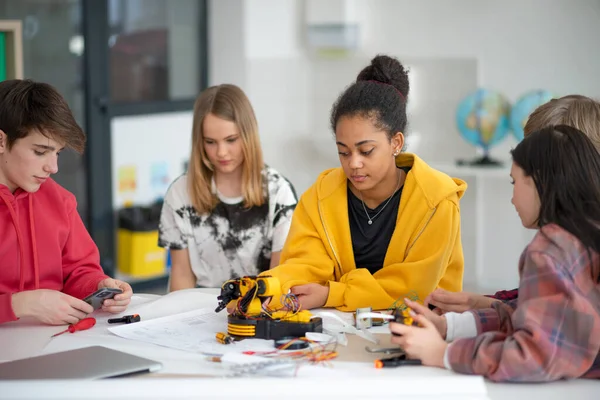 ロボット教室で電気玩具やロボットを構築しプログラミングする学生のグループ — ストック写真