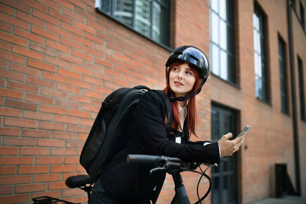 A portrait of businesswoman commuter on the way to work with bike, sustainable lifestyle concept.