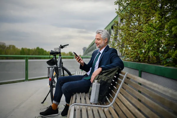 一个骑自行车的商人坐在长椅上 用智能手机 换乘和替代运输概念 — 图库照片