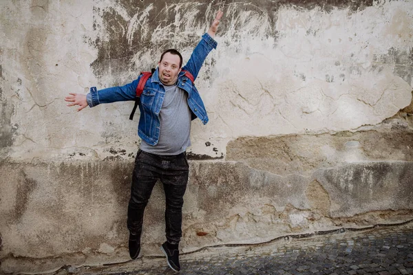 Веселий Молодий Чоловік Даун Сіджромом Стрибає Вулиці Перед Стіною Піднятою — стокове фото
