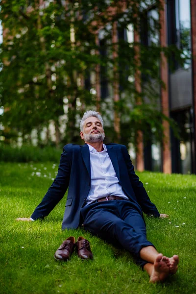 一个成熟的商人 光着脚在公园里休息和坐着 自由自在 逃避工作 工作生活平衡的概念 — 图库照片