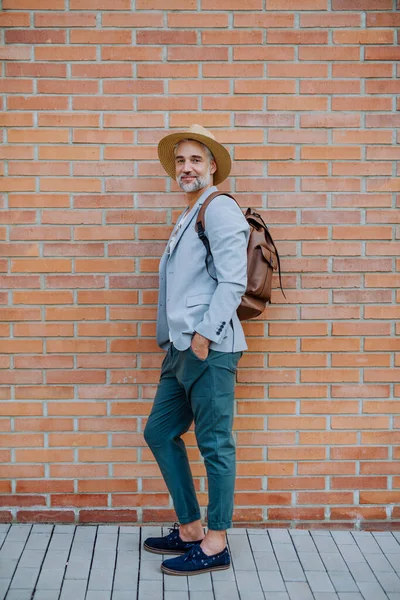 カメラを見ながら藁帽子とリュックを身に着けている自信のある男の肖像画 仕事に向かう途中の夏にカジュアルな服を着たビジネスマン — ストック写真