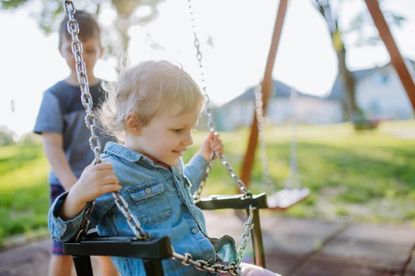 Little Sibling Playing Together Playground Swaying Swing Enjoying Sunny Summer — Zdjęcie stockowe