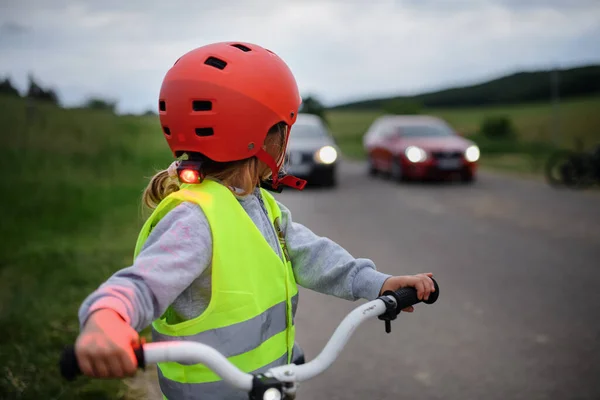 Вид Сзади Маленькую Девочку Отражающем Жилете Велосипеде Дороге Автомобилями Позади — стоковое фото