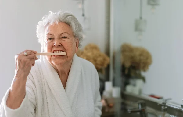 Ηλικιωμένη Γυναίκα Καθαρίζει Δόντια Της Μια Ξύλινη Βούρτσα Στο Μπάνιο — Φωτογραφία Αρχείου