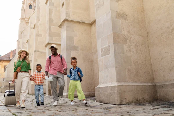 Счастливая Многорасовая Семья Путешествует Чемоданами Прогуливаясь Старому Центру Города — стоковое фото