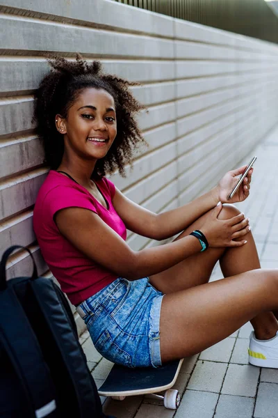 Multiracial Teenage Girl Backpack Sitting Skateboard Using Phone Summer Day — Zdjęcie stockowe