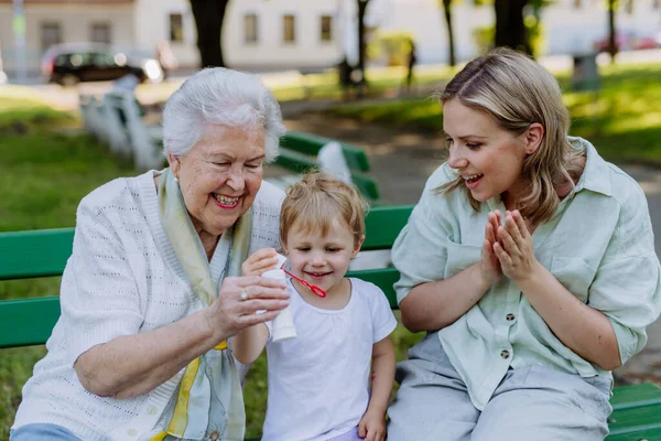 Egy Boldog Mosolygós Idősebb Nagymamával Kislányával Aki Szappanbuborékokat Fúj Parkban — Stock Fotó