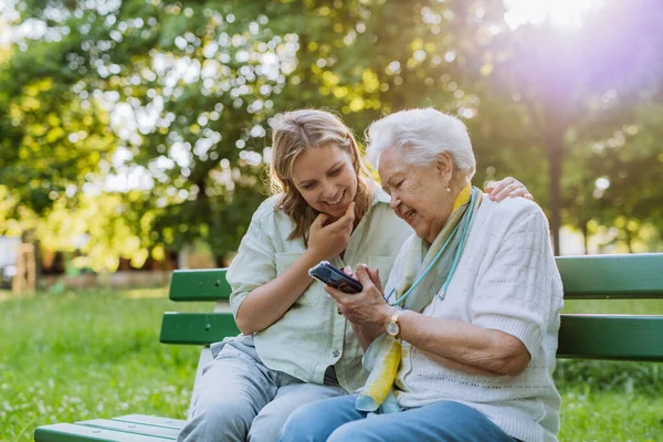 Взрослый Дедушка Помогает Бабушке Пользоваться Мобильным Телефоном Сидя Летом Скамейке — стоковое фото