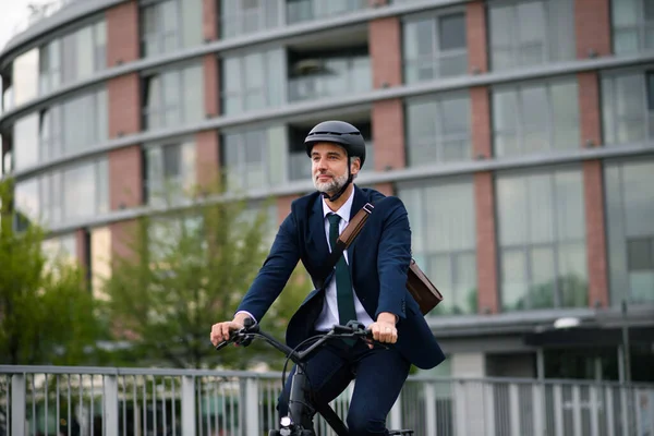 A businessman commuter on the way to work, riding bike in city, sustainable lifestyle concept.