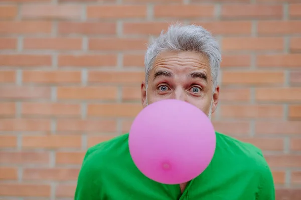 Fun Portrait Happy Energetic Mature Man Inflating Pink Balloon Street — Stockfoto