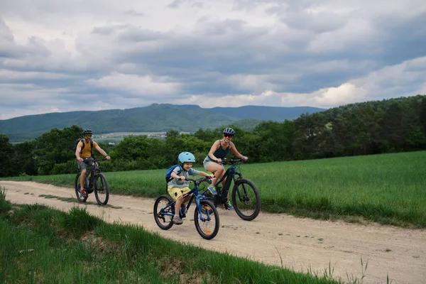 夏に村の路上で自転車に乗っている小さな子供を持つ若い家族 — ストック写真