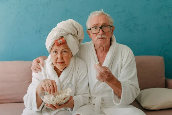 Happy Senior Couple Sitting Sofa Bathrobes Watching Popcorn — Fotografia de Stock