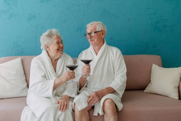 Happy Senior Couple Sitting Together Bathrobe Sofa Glass Wine Having — Stock Fotó