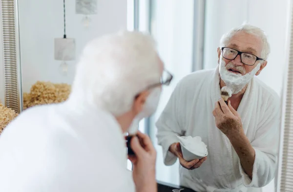 Senior Man Shaving His Beard Bathroom Looking Mirror Morning Routine — Foto de Stock