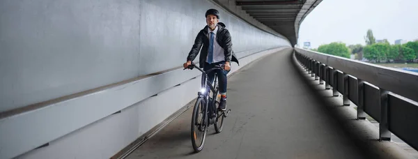 Businessman commuter on the way to a work, riding bike over bridge, sustainable lifestyle concept.