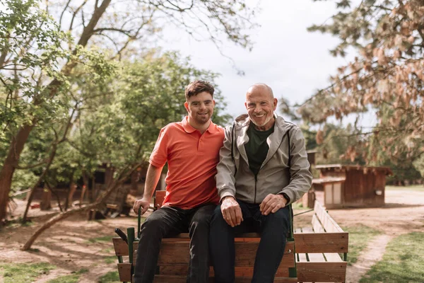 Happy Senior Father His Young Son Syndrome Embracing Sitting Park — ストック写真