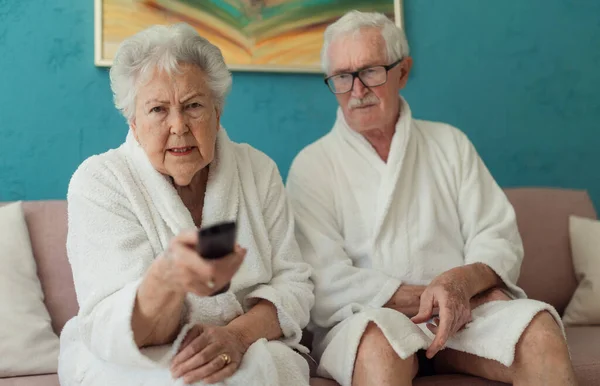Happy Senior Couple Sitting Sofa Bathrobes Watching — Stok fotoğraf