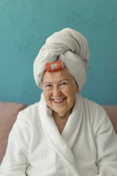 Happy Senior Woman Plastic Curler Sitting Sofa Bathrobes Looking Camera — Stok fotoğraf